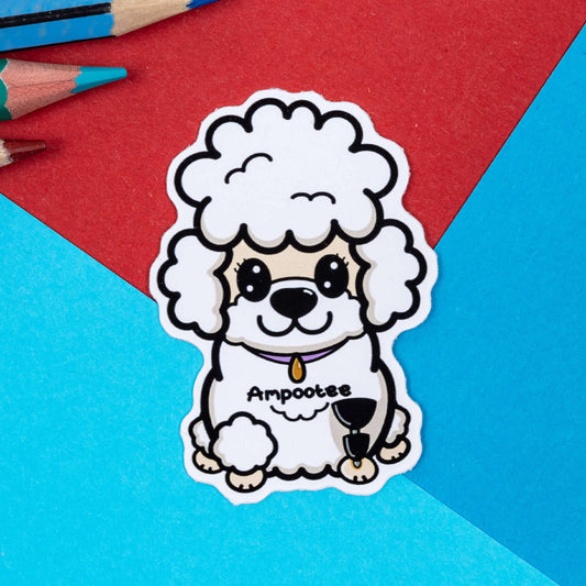 The Ampootee Poodle Dog Sticker - Amputee on a red and blue background with colouring pencils. The white smiling poodle dog sticker has prosthetic front leg with black text across its middle reading 'ampootee'. The hand drawn design is raising awareness for limb loss and amputees.