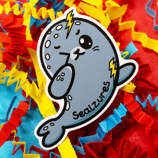 Adorable Sealzures sticker by Innabox featuring a cute grey seal with lightning bolts and a playful expression to represent seizure awareness. Surrounded by colourful confetti, this waterproof gloss vinyl sticker is approx 5 cm tall and custom cut. A kind and funny design to support those living with epilepsy or hidden disabilities.