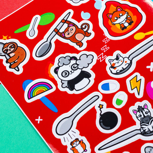 Close up of the Spoonie Sticker Sheet - A6 Sticker Sheet on a red, blue and green background. The red a6 vinyl sticker sheet features cute animal illustrations with hidden illnesses represented with spoons, flames, storm clouds, rainbows and pills. The hand illustrated designs are for raising awareness for invisible illnesses.