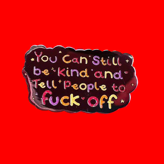 The You Can Still be Kind and Tell People to F**k Off Enamel Pin on a red background. The silver plated enamel pin has rainbow writing reading 'you can still be kind and tell people to fuck off' with multicoloured sparkles, dots and stars.