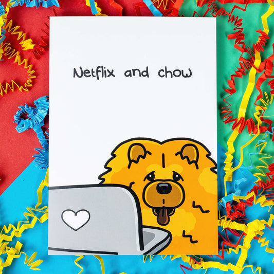 A white card with a drawing of a ginger Chow Cow dog in the bottom corner on a laptop above it there's black text that says Netflix and chow. The punny card is on a red, blue and green background with blue, yellow and red crinkle card confetti.
