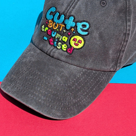 Close-up flat lay of the Hot and Neuro-Spicy cap from Innabox, highlighting the vibrant embroidered slogan and textured washed cotton fabric under bright natural light.