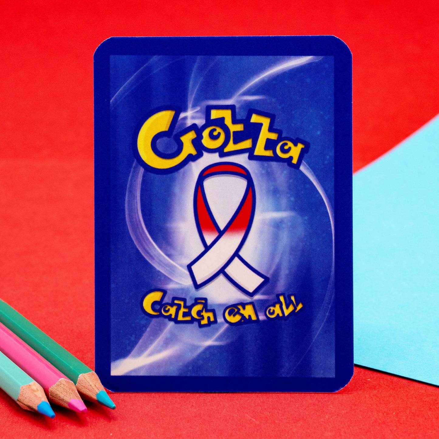 Reverse side of an Innabox Neurodivergent Trading Card featuring a blue swirl design, charity ribbon logo, and playful “Gotta Catch Em All” slogan. Retro trading card style backing used for collectable cards that highlight neurodivergence and hidden disabilities.