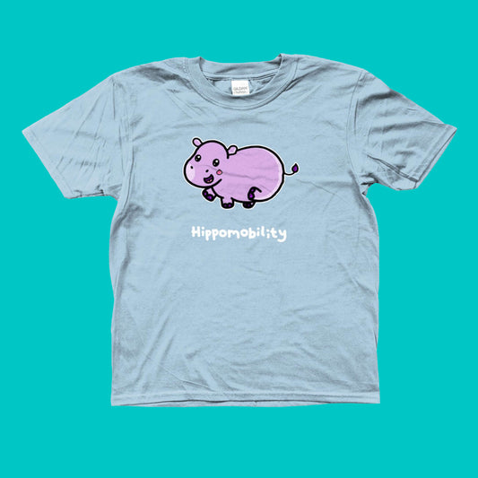 Hippomobility - Hyper Mobility Kids Tee shown on a blue background. The light blue t-shirt has an illustration of a pink happy hippo with 'hippomobility' in white text underneath. The hand drawn design is made to raise awareness for hyper mobility.