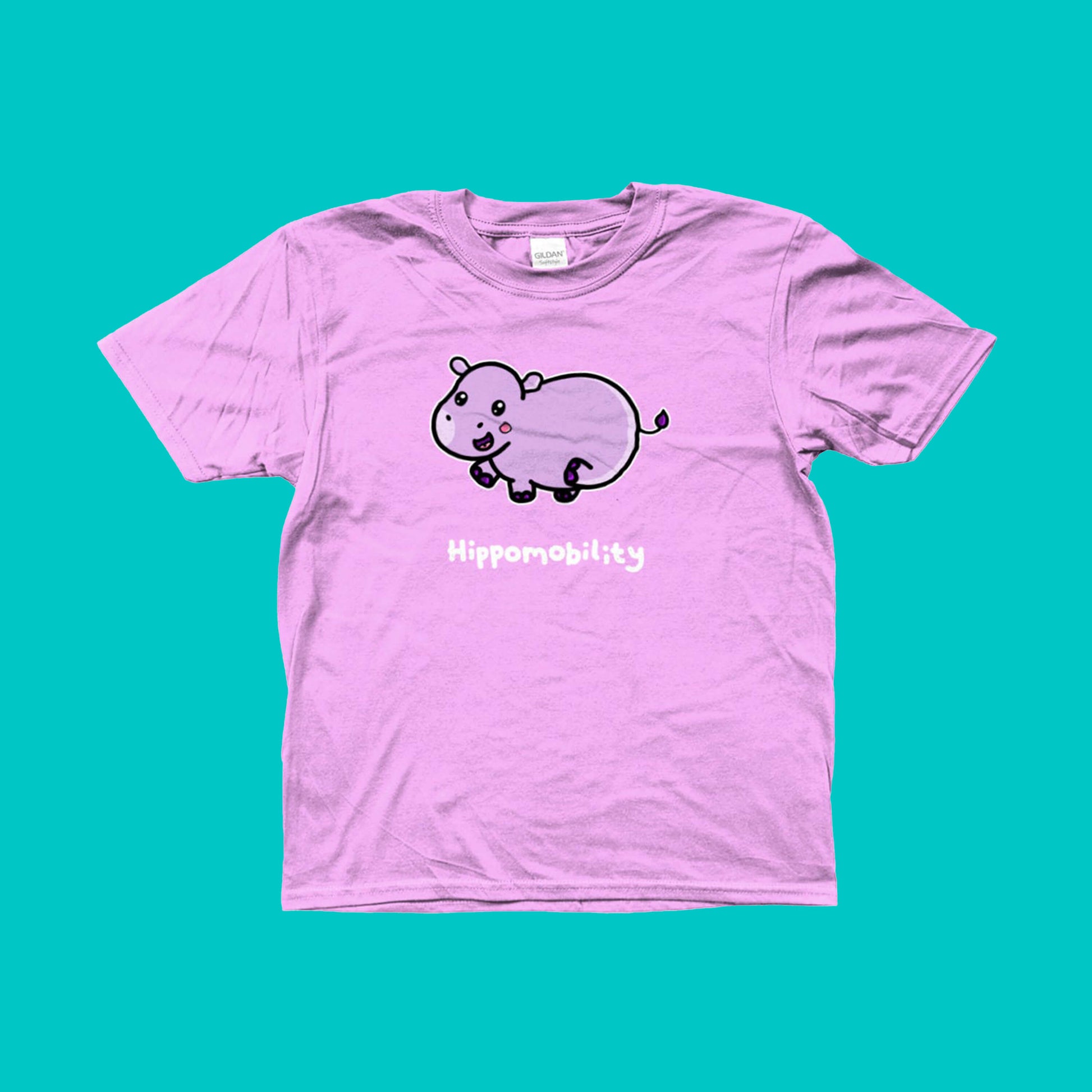 Hippomobility - Hyper Mobility Kids Tee shown on a blue background. The light pink t-shirt has an illustration of a pink happy hippo with 'hippomobility' in white text underneath. The hand drawn design is made to raise awareness for hyper mobility.