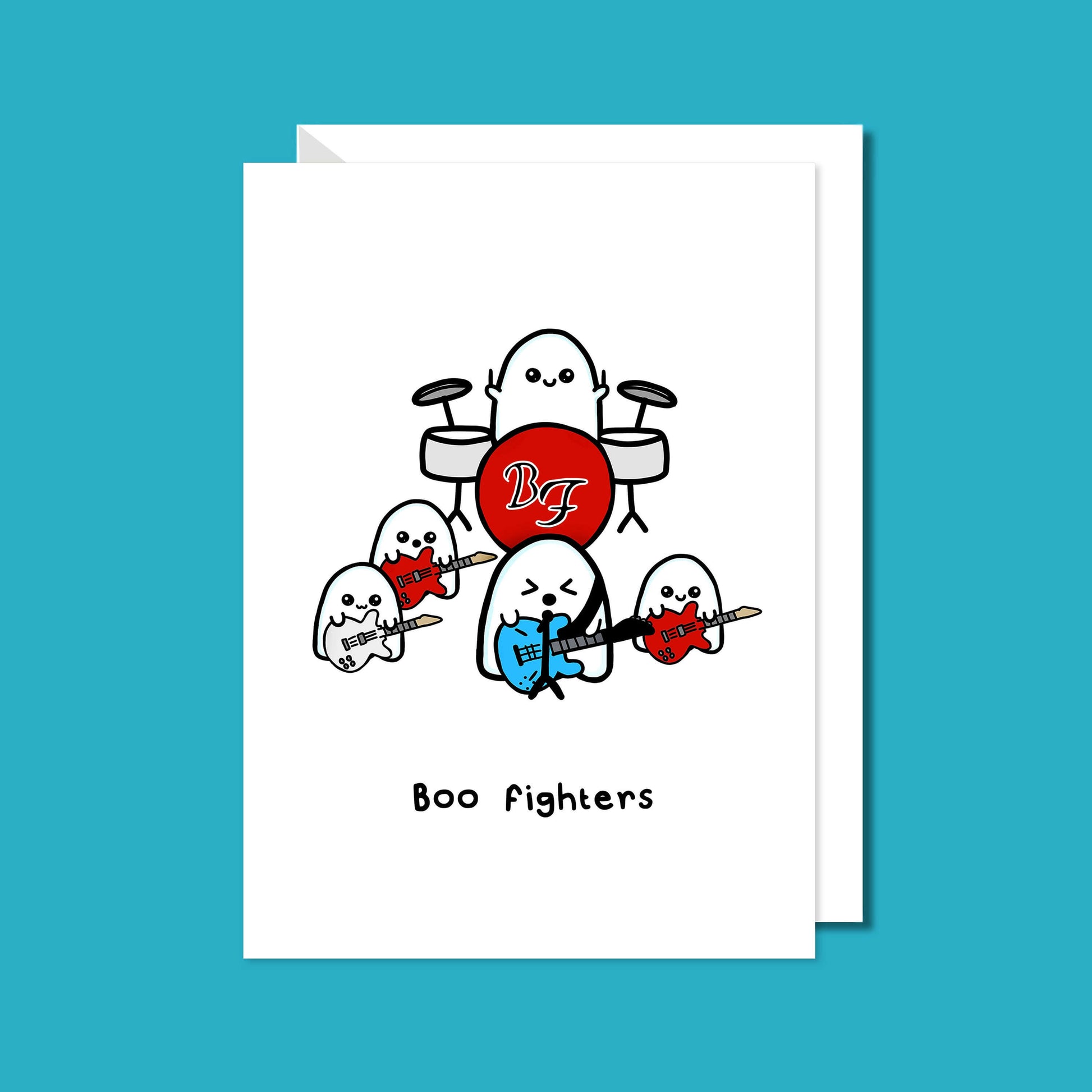 Close up of the Boo Fighters Birthday Card on a blue background with a white envelope underneath. A white card with a kawaii ghost band playing blue, white and red guitars and a red Boo Fighters drum kit, underneath reads Boo Fighters in black text.