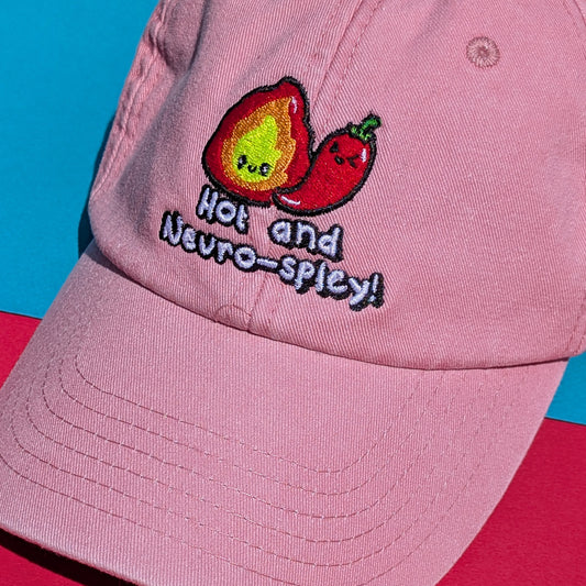 Close-up of the Hot and Neuro-Spicy embroidery by Innabox on a pink cotton cap. Shows flame and chilli characters, ideal for neurodivergent fashion lovers.