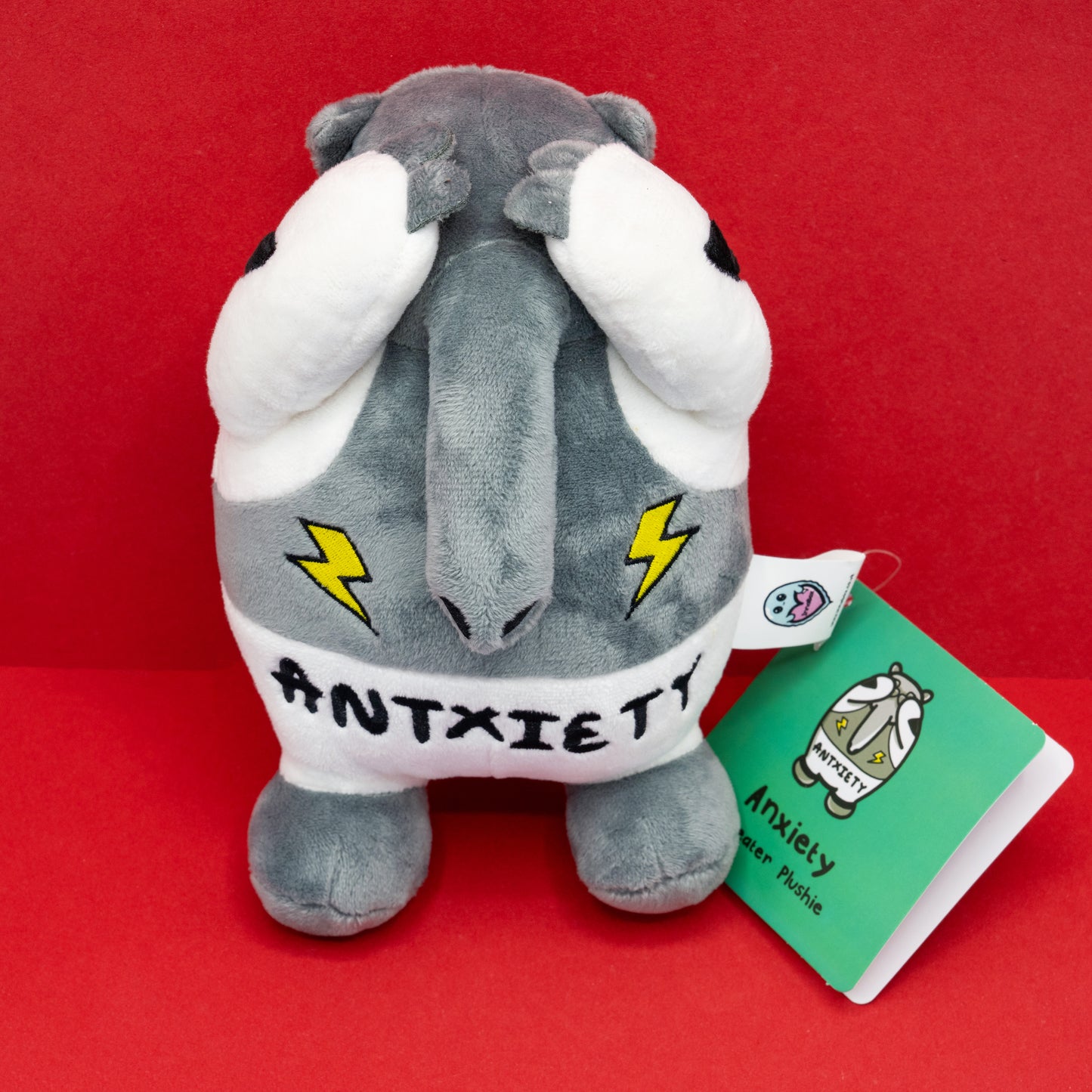 Front view of the Antxiety Anteater Plush Toy with hands covering its eyes, symbolising overwhelm. Created by Innabox to support those with anxiety and hidden disabilities through cute, relatable design.