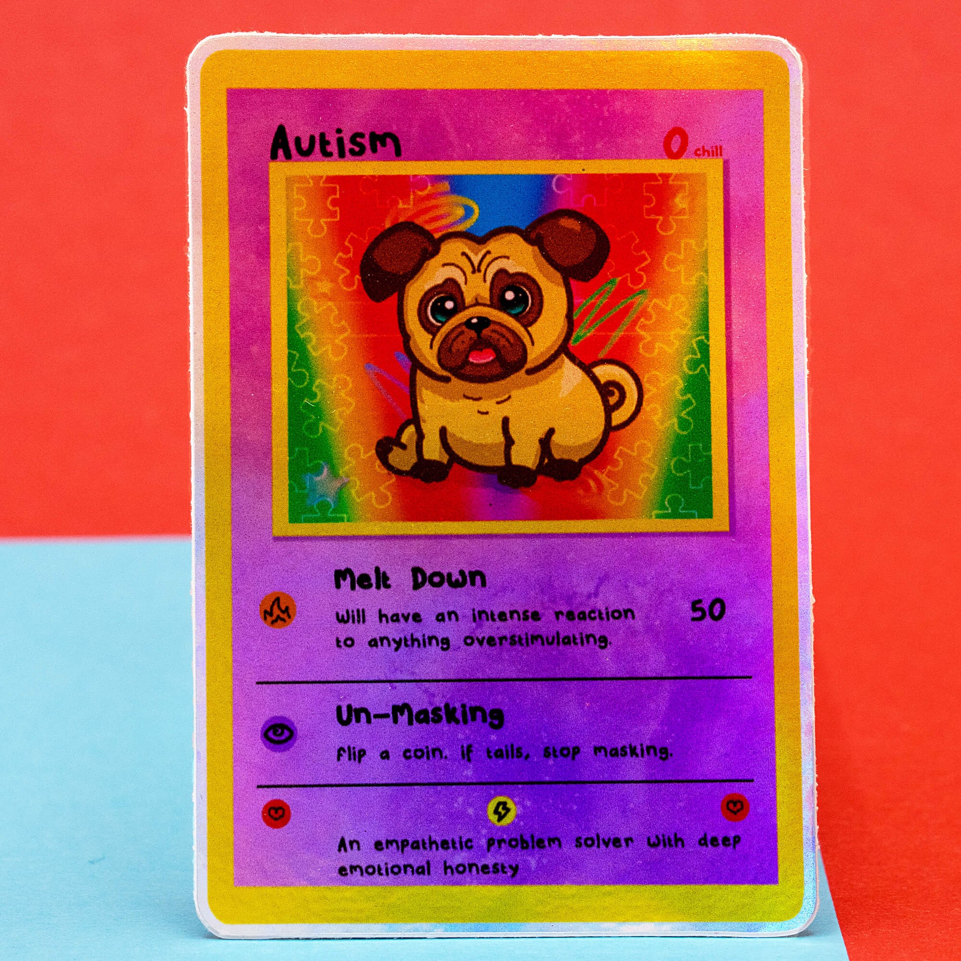 A clear product photo of the Innabox Neurodivergent Collectable Trading Card Sticker – Autism, showing the illustrated pug character on a colourful puzzle-piece background. The card lists traits such as Melt Down and Un-Masking. Shot on a bright red and blue background, ideal for fans of uplifting, disability-inspired stationery and neurodivergent collectables.