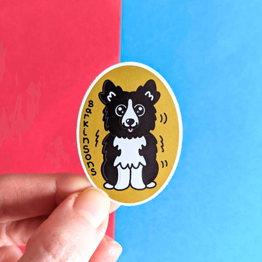 Barkinsons Disease Sticker - Parkinsons being held over a red and blue background. The sticker is yellow and oval shaped with a black and white fluffy dog in the middle sat down with big sparkly eyes and pink tongue hanging out. There are black squiggles around the dog and 'Barkinsons' written in black vertical letters. The design is to raise awareness for parkinson's disease.