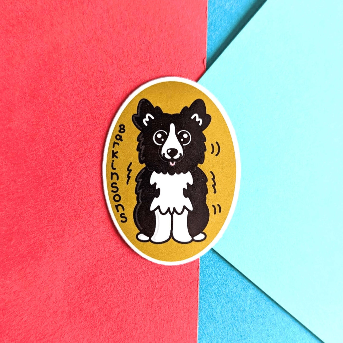 Barkinsons Disease Sticker - Parkinsons on a red, blue and green background. The sticker is yellow and oval shaped with a black and white fluffy dog in the middle sat down with big sparkly eyes and pink tongue hanging out. There are black squiggles around the dog and 'Barkinsons' written in black vertical letters. The design is to raise awareness for parkinson's disease.