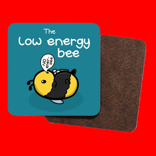 The Low Energy Bee Coaster shown in front of a red backdrop. The coaster is square in shape with a teal blue colour and 'The low energy bee' written in big letters at the top in white letters. Under the writing is a cute yellow and black bee lying on it's wings with its arms, legs, little belly and stinger in the air. The bee has a speech bubble coming from it's mouth with 'NO ener-bee' written inside in black writing.