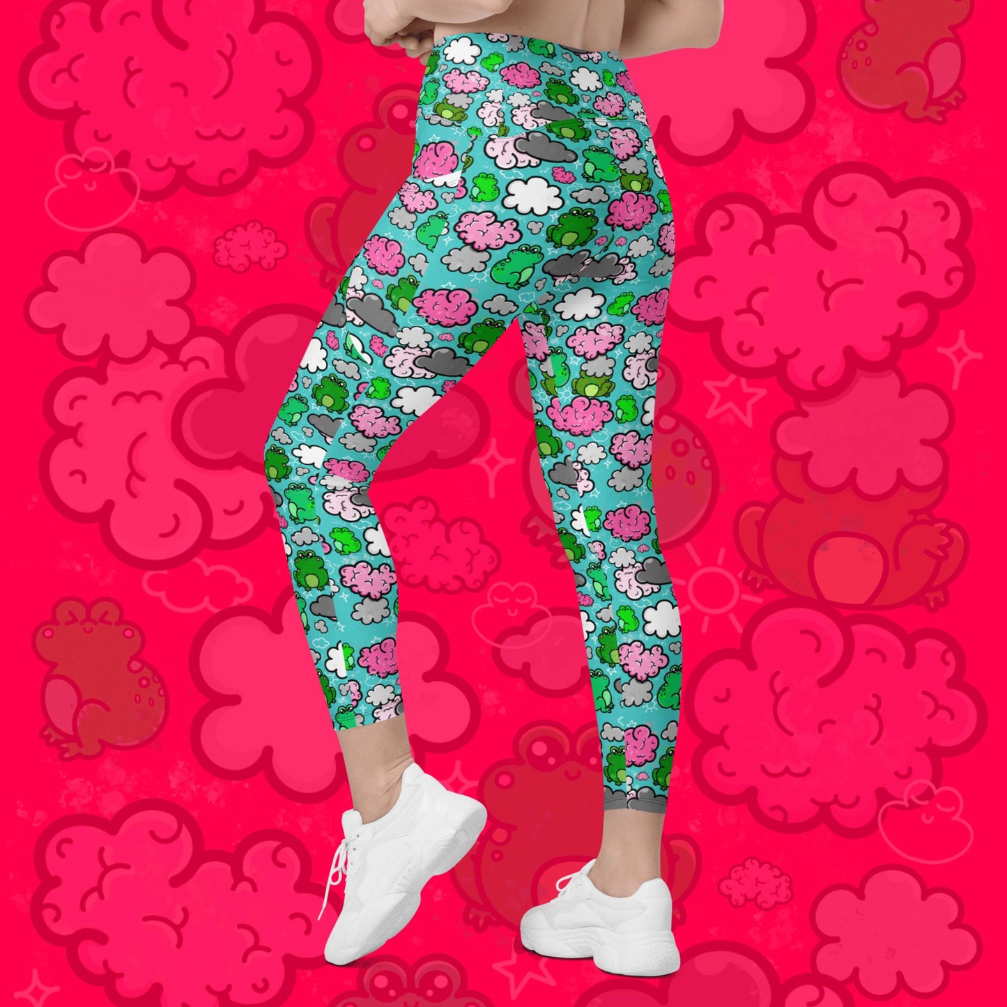 The Brain Frog Leggings with pockets - Brain Fog being worn by a model facing away with their left leg bent on a red background with a faded brain frog print, the photo is cropped from the hips down. The leggings are an aqua blue base with various green kawaii face frogs with pink blush cheeks, pink brain style clouds, white and grey clouds and white sparkles all over. The design was created to raise awareness of Brain Fog.