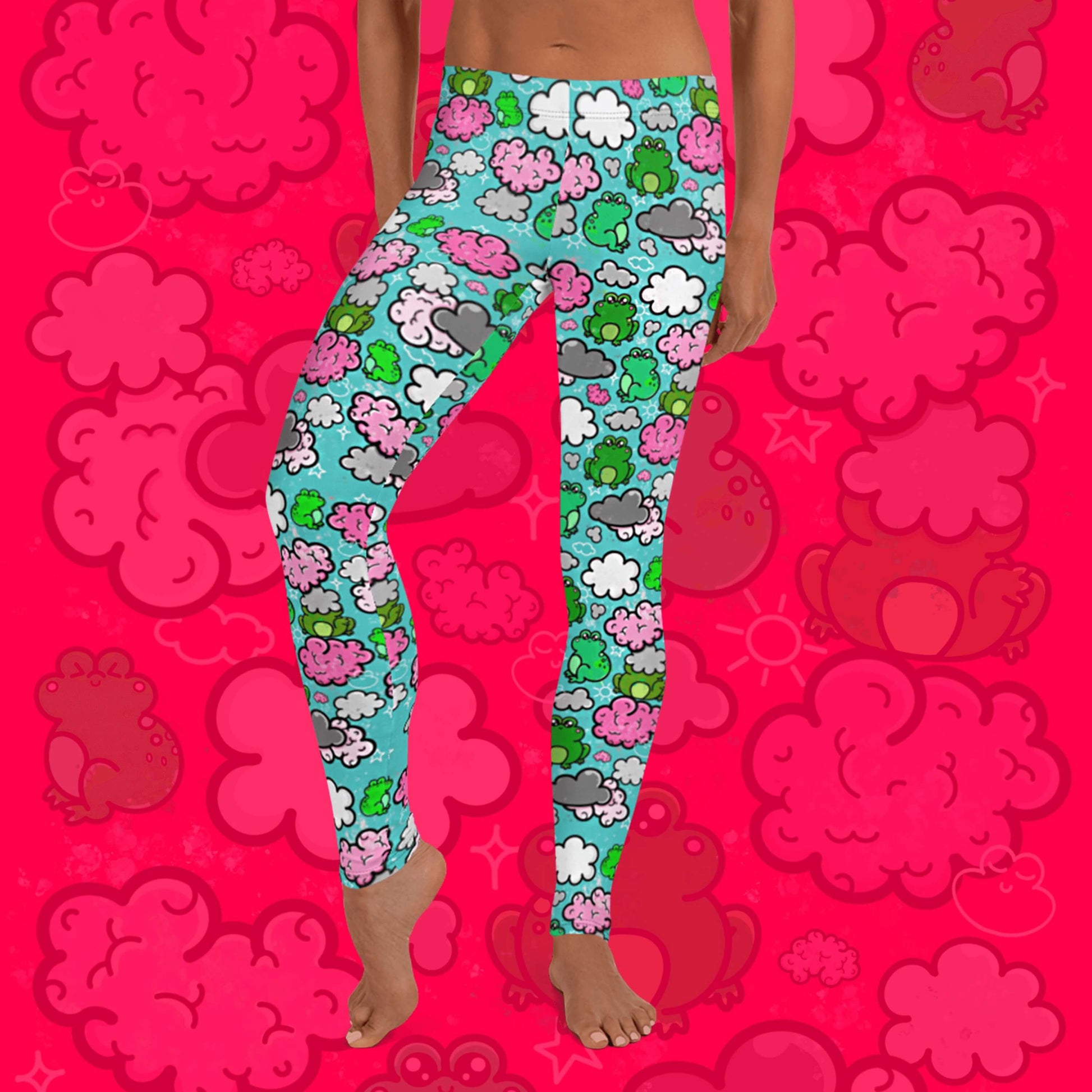 The Brain Frog Leggings - Brain Fog being worn by a model facing forward with their left leg bent on a red background with a faded brain frog print, the photo is cropped from the hips down. The leggings are an aqua blue base with various green kawaii face frogs with pink blush cheeks, pink brain style clouds, white and grey clouds and white sparkles all over. The design was created to raise awareness of Brain Fog.