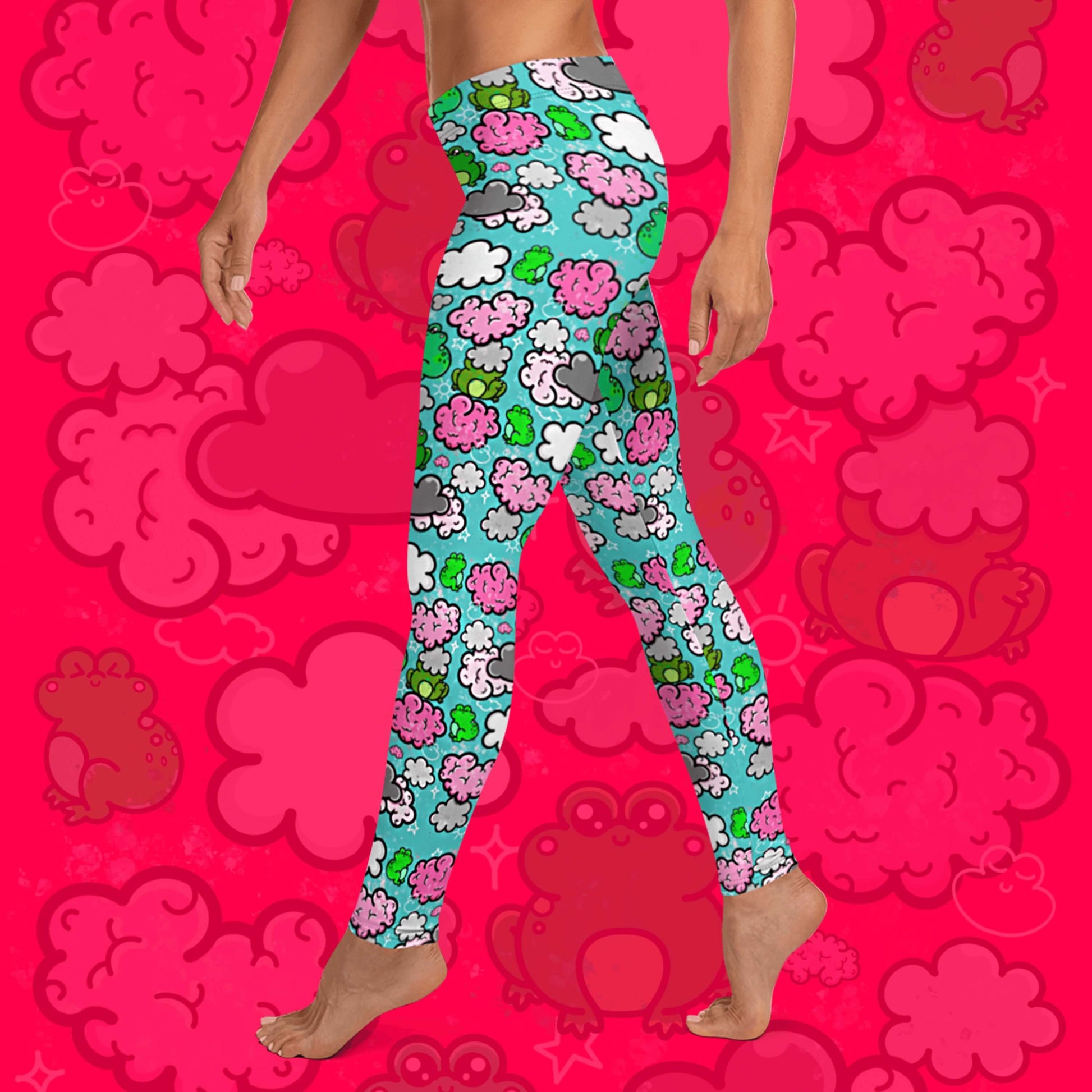 The Brain Frog Leggings - Brain Fog being worn by a model walking left on a red background with a faded brain frog print, the photo is cropped from the hips down. The leggings are an aqua blue base with various green kawaii face frogs with pink blush cheeks, pink brain style clouds, white and grey clouds and white sparkles all over. The design was created to raise awareness of Brain Fog.