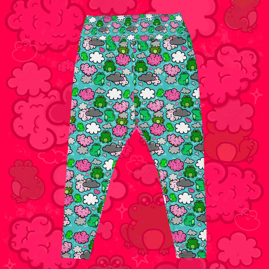 The Brain Frog Plus Size Leggings - Brain Fog on a red background with a faded brain frog print. The leggings are an aqua blue base with various green kawaii face frogs with pink blush cheeks, pink brain style clouds, white and grey clouds and white sparkles all over. The design was created to raise awareness of Brain Fog.
