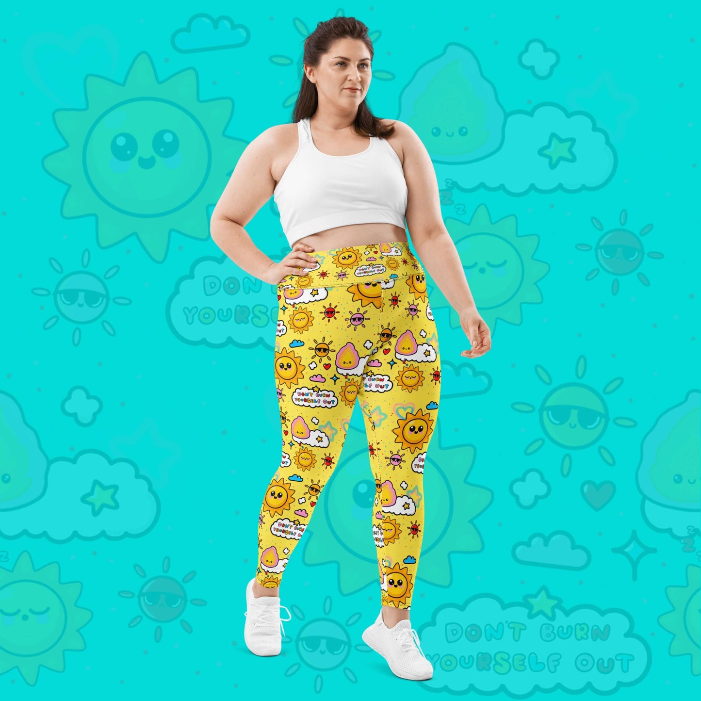 The Don't Burn Yourself Out Plus Size Leggings on a model over an aqua blue background with a faded don't burn yourself print overlayed. The model is facing forward taking a step forward and one hand resting on their hip whilst smiling off to the right. The print is yellow with various kawaii face sunshines, sparkles, hearts, pink flames and pink, blue and white clouds with don't burn yourself out inside in rainbow. Design inspired by the self care movement.