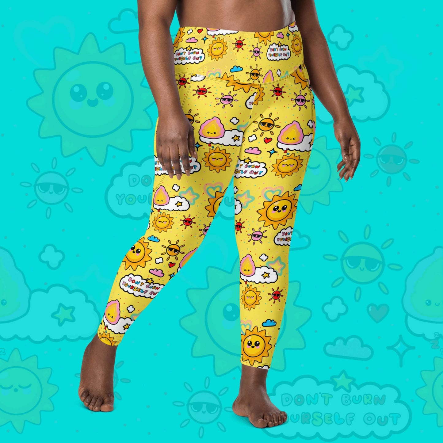 The Don't Burn Yourself Out Leggings with pockets on a model over an aqua blue background with a faded don't burn yourself print overlayed. The model is facing forward taking a step forward and both hands resting by their side. The print is yellow with various kawaii face sunshines, sparkles, hearts, pink flames and pink, blue and white clouds with don't burn yourself out inside in rainbow. Design inspired by the self care movement.