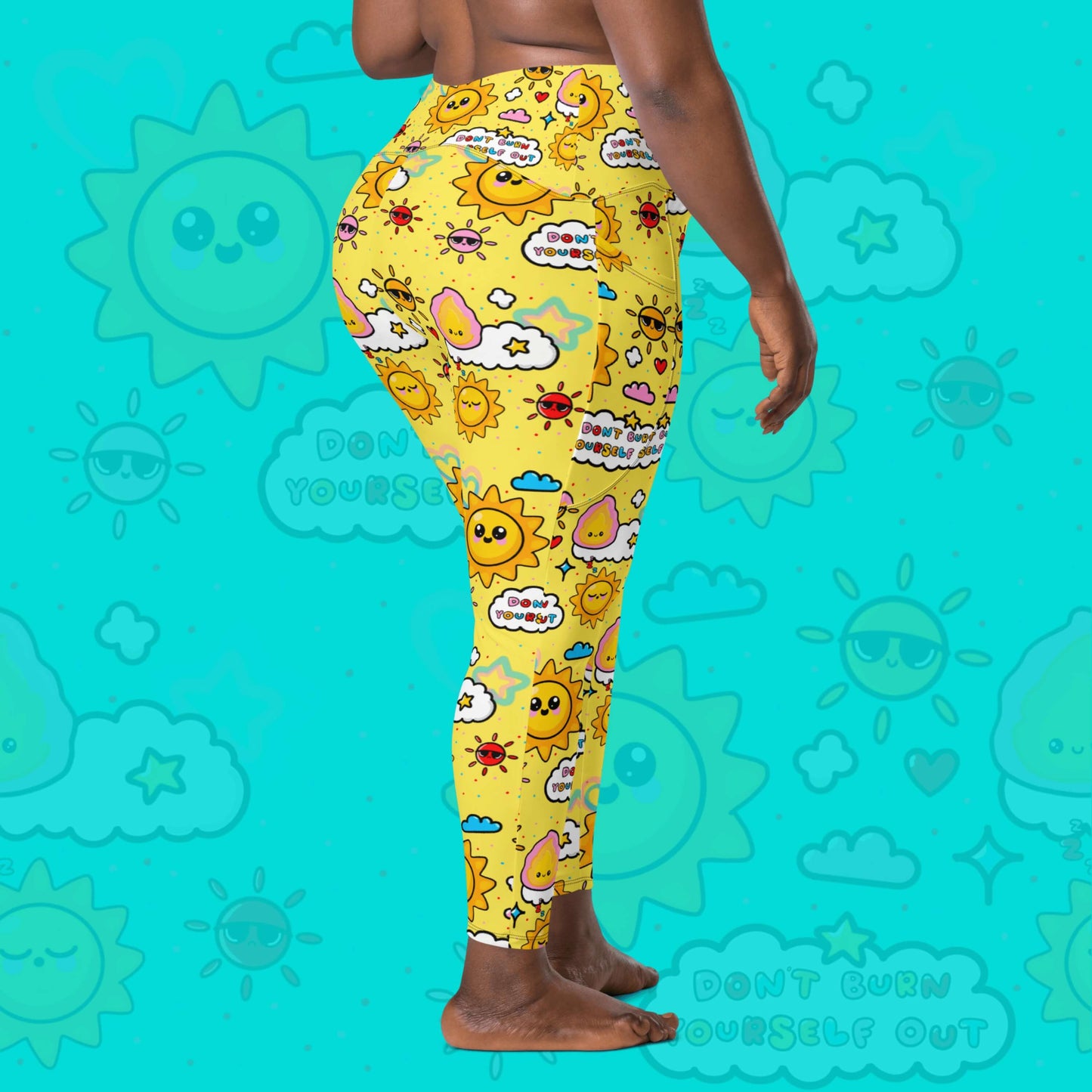 The Don't Burn Yourself Out Leggings with pockets on a model over an aqua blue background with a faded don't burn yourself print overlayed. The model is facing away taking a step and both hands resting by their side. The print is yellow with various kawaii face sunshines, sparkles, hearts, pink flames and pink, blue and white clouds with don't burn yourself out inside in rainbow. Design inspired by the self care movement.