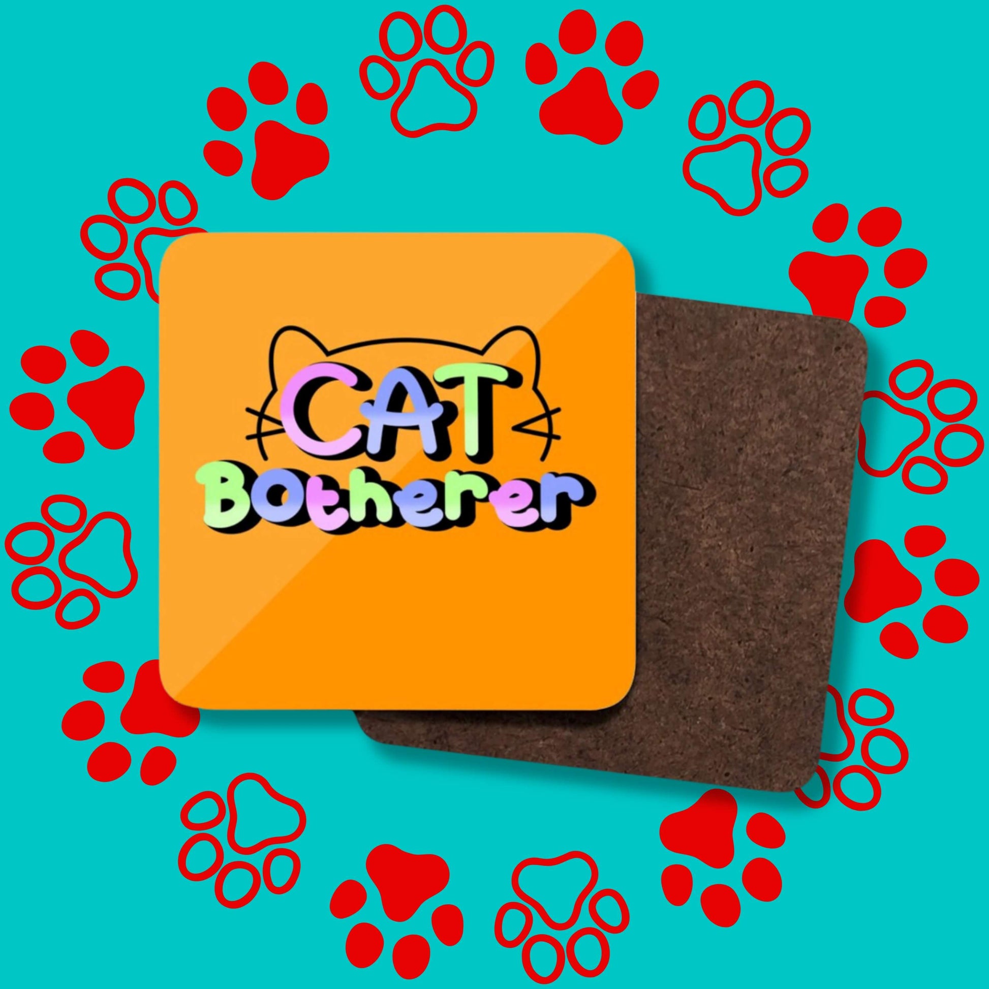 A collage of the Cat Botherer Coaster facing forward and backwards to show the plain wooden back on a red and blue paw print background. The orange wooden coaster has rounded edges and pastel rainbow text reading 'cat botherer' and a black cat head outline.
