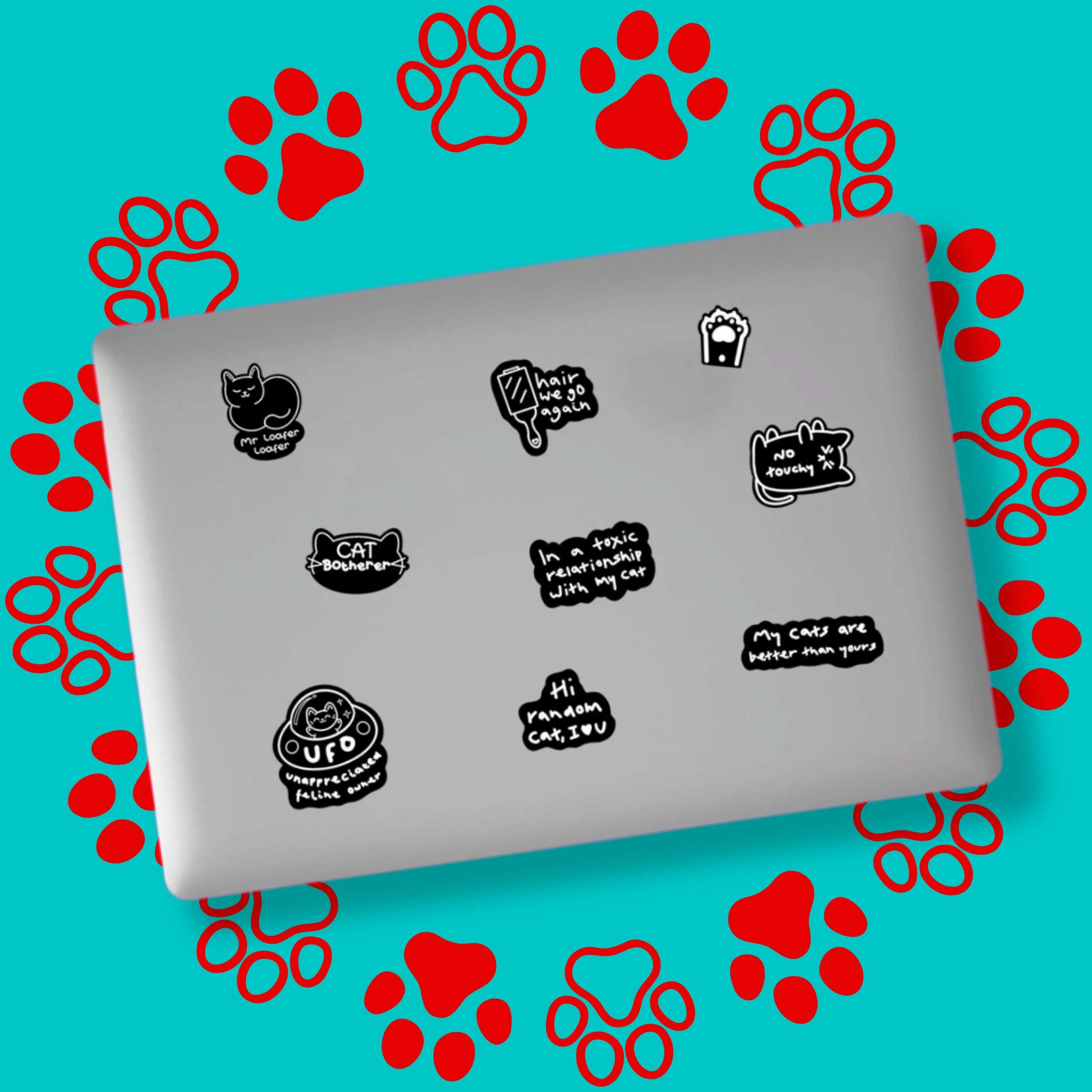 The Cat Parent Sticker Sheet - A6 Sticker Sheet stuck randomly all over a silver laptop on a red and blue paw print background. The sticker sheet features black and white stickers with a cat theme such as 'cat botherer', 'hair we go again', 'hi random cat I love u', paws, cats and more.