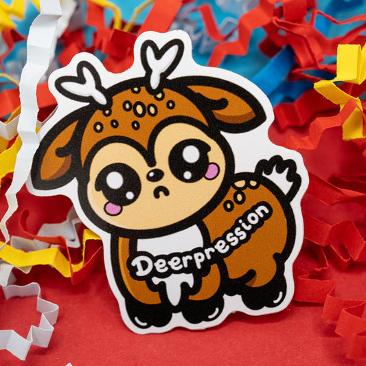 A cute vinyl sticker of a sad cartoon deer with tiny antlers, blushing cheeks, and big shiny eyes. The word “Deerpression” is written across its body in bold white letters. The sticker sits among red, yellow, and white paper confetti on a bright background. Designed by Innabox, this Deerpression 2.0 sticker represents depression with care and humour, created to uplift those with chronic illnesses or hidden disabilities.