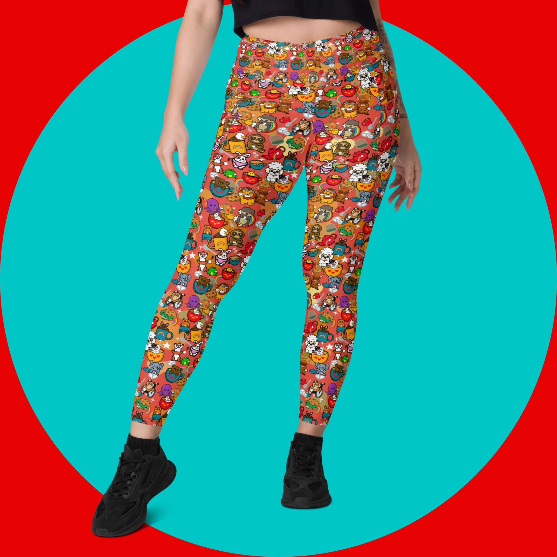 The Disabili Tea and Biscuits - Disability Leggings with pockets being modelled by a femme person wearing a black tee and black trainers on a red and blue background. The leggings feature various disabled and chronically ill animal characters drinking tea, sitting in tea mugs and holding up mugs. There is also various cookie biscuits, tea bags, sugar cubes, teapots, rainbows, sparkles and tea spills all underneath. The leggings are a punny gift raising awareness for disabilities.