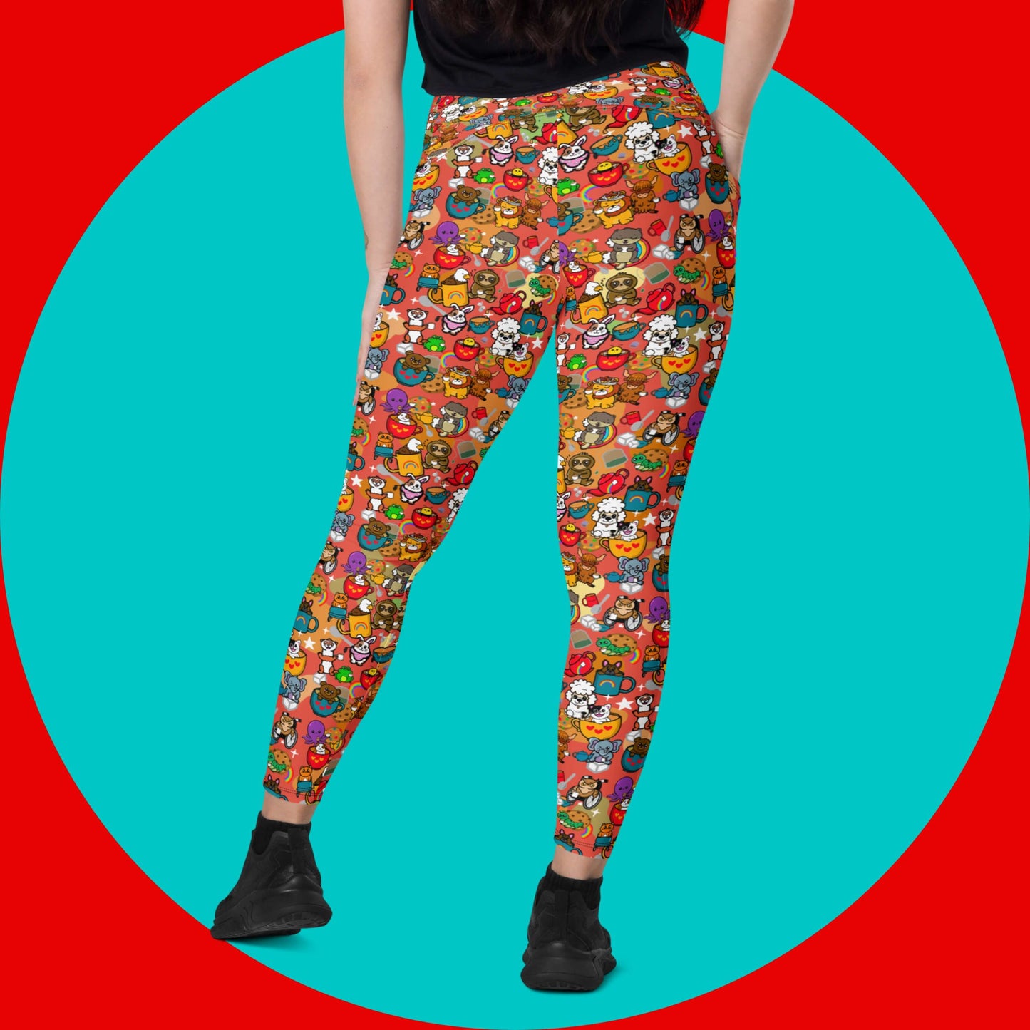 The Disabili Tea and Biscuits - Disability Leggings with pockets being modelled by a femme person wearing a black tee and black trainers on a red and blue background. The leggings feature various disabled and chronically ill animal characters drinking tea, sitting in tea mugs and holding up mugs. There is also various cookie biscuits, tea bags, sugar cubes, teapots, rainbows, sparkles and tea spills all underneath. The leggings are a punny gift raising awareness for disabilities.
