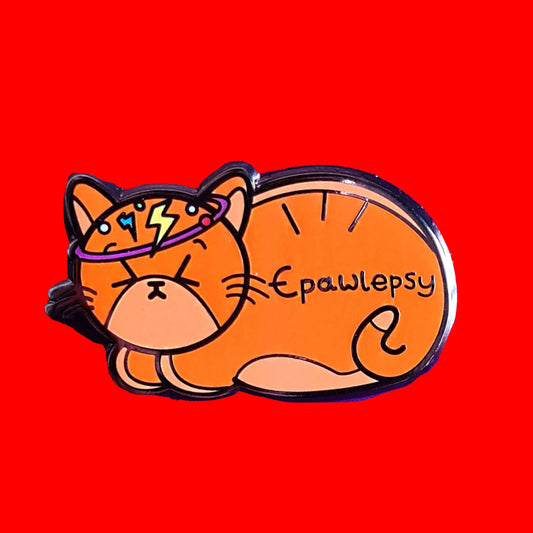 Epawlepsy Enamel Pin - Epilepsy on a red background. The enamel pin is a ginger cat with eyes scrunched closed and symbols to represent a dizzy spell drawn across his head. Epawlepsy is written on the cats stomach. Enamel pin is designed to raise awareness for epilepsy