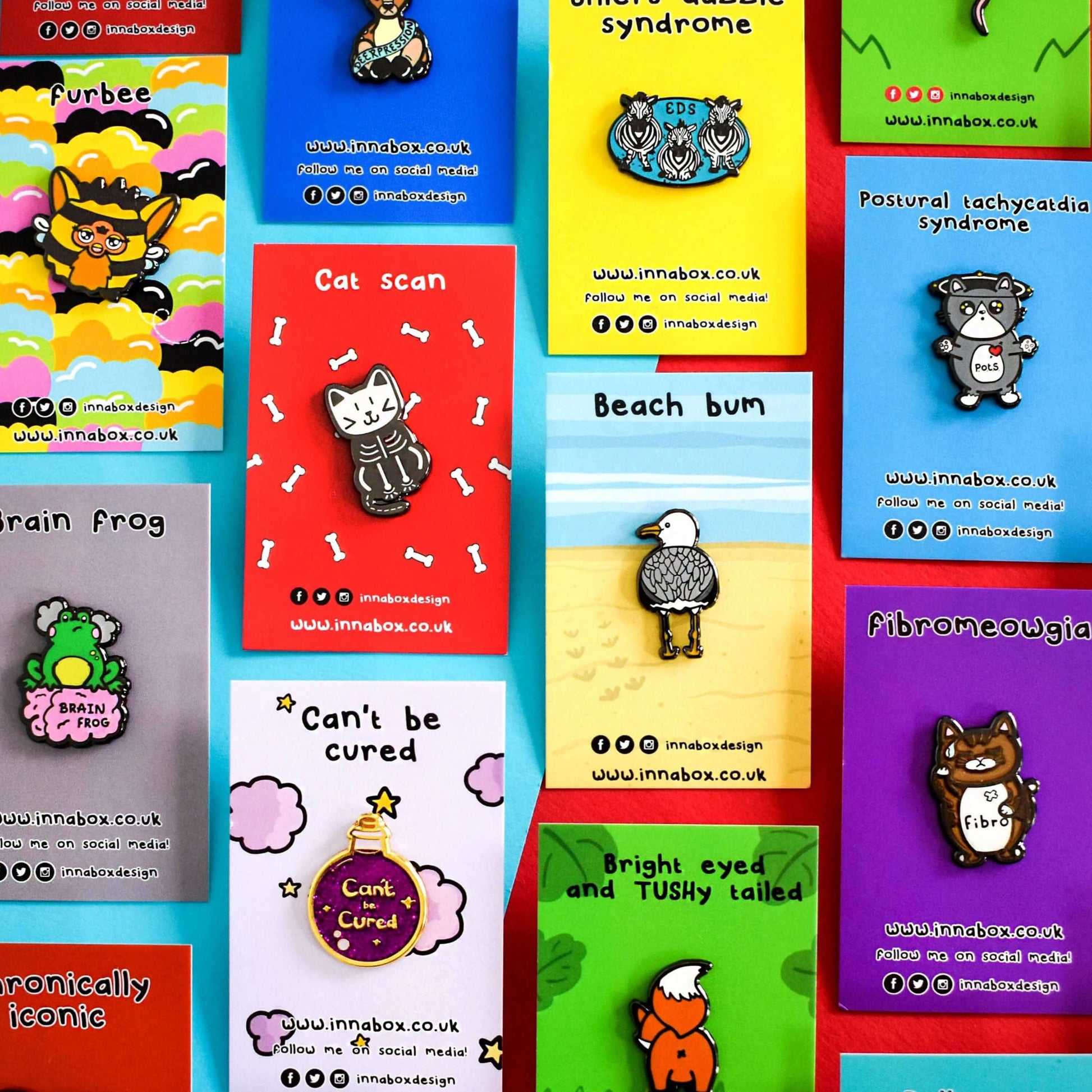 An array of Innabox enamel pins shown on backing card on a red background. Choose from any three pins. Enamel pins designed to raise awareness for chronic illnesses