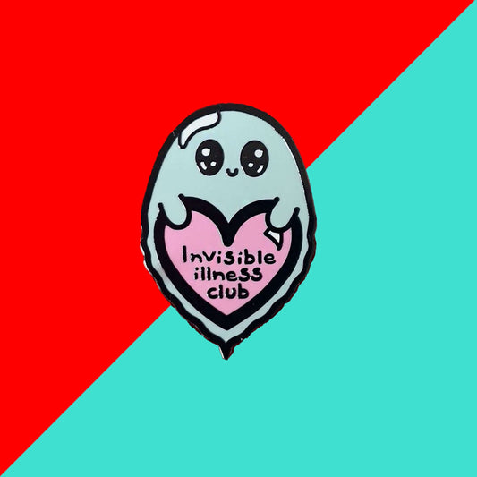 Invisible Illness Club Enamel Pin shown on a red and blue background. The enamel pin is of a cute smiling ghost holding a pink heart with text saying invisible illness club. The enamel pin is designed to raise awareness for hidden and chronic illnesses