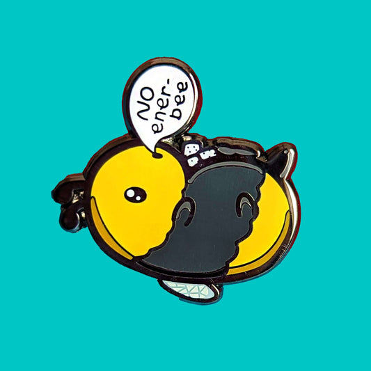 Low Energy Bee Enamel Pin on a blue background. The enamel pin is a cute yellow and black bee lying on it's wings with its arms, legs, little belly and stinger in the air. The bee has a speech bubble coming from it's mouth with 'NO ener-bee' written inside in black writing. Hand drawn design made to raise awareness for chronic fatigue.