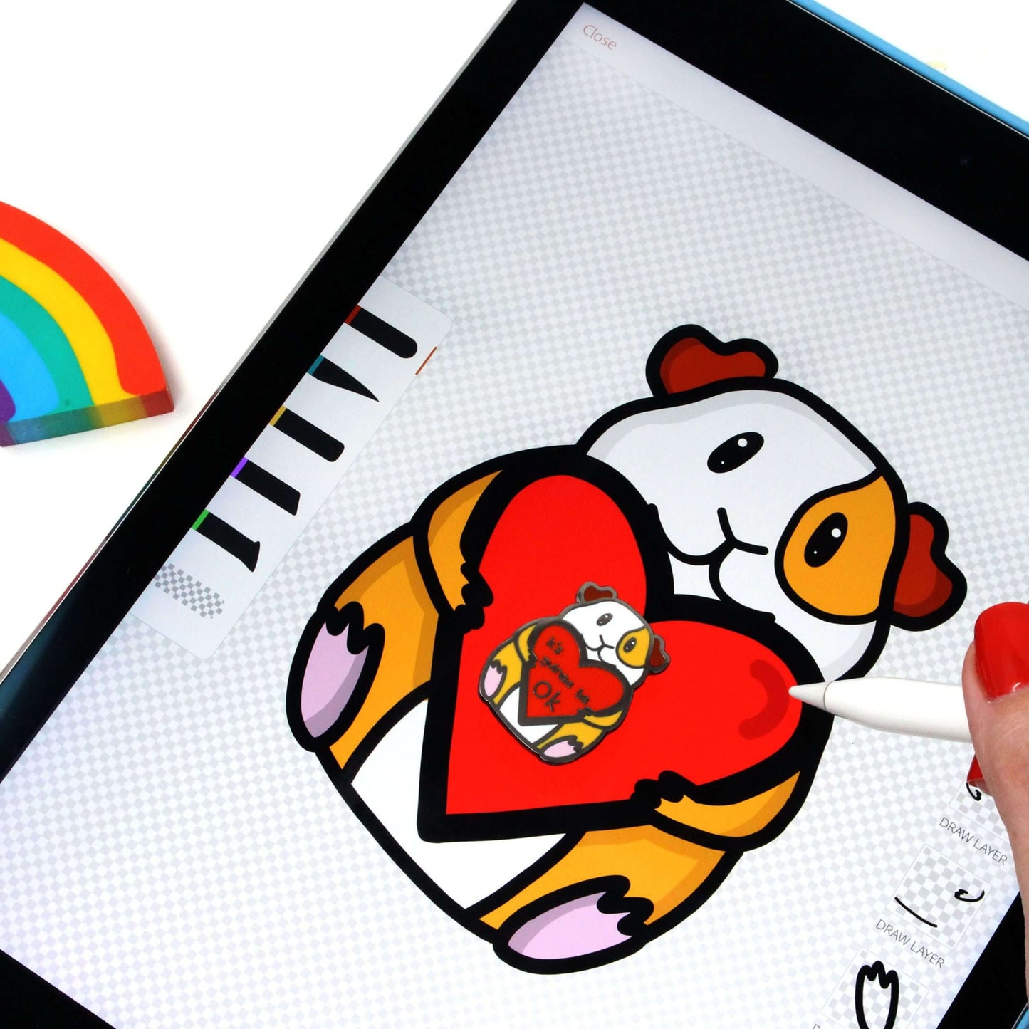 illustration for Guinea Pig Mental Health Enamel Pin being drawn on iPad. The enamel pin is of a smiling guinea pig holding a big red heart with the text it's guinea be ok inside. The enamel pin is deigned to raise awareness for mental health.