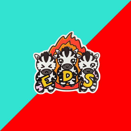 A sticker with three zebras on with a flame behind them and they are holding letters spelling EDS it is on a red and blue background. Hand drawn design is raising awareness for Ehlers-Danlos Syndrome.