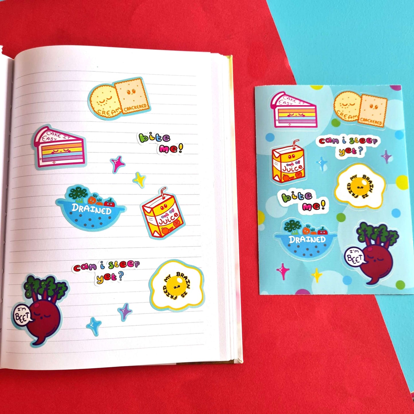 The Fatigued Foods Sticker Sheet - A6 Sticker Sheet on a red and blue background. Sticker sheet of a smiling rainbow cake with text reading 'cake it easy', two snoozing cream crackers with text reading 'cream crackered', a sad fruit juice box with text 'out of juice', a sad fried egg with text 'my brain is fried', a sieve filled of sad vegetables with the text 'drained', a sleeping beetroot with a speech bubble reading 'I'm beet' as well as rainbow text reading 'can I sleep yet?' and 'bite me'.