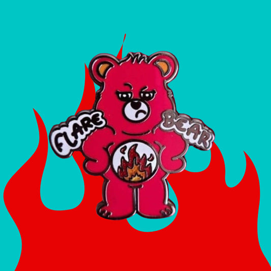 Flare Bear enamel pin shown on a red and blue background. The enamel pin is of a red bear with a fed up expression and hands on its hips. There is a white circle on its belly with flames inside. Flare Bear is written on the pin. The enamel pin is designed to raise awareness for chronic illness flare ups.