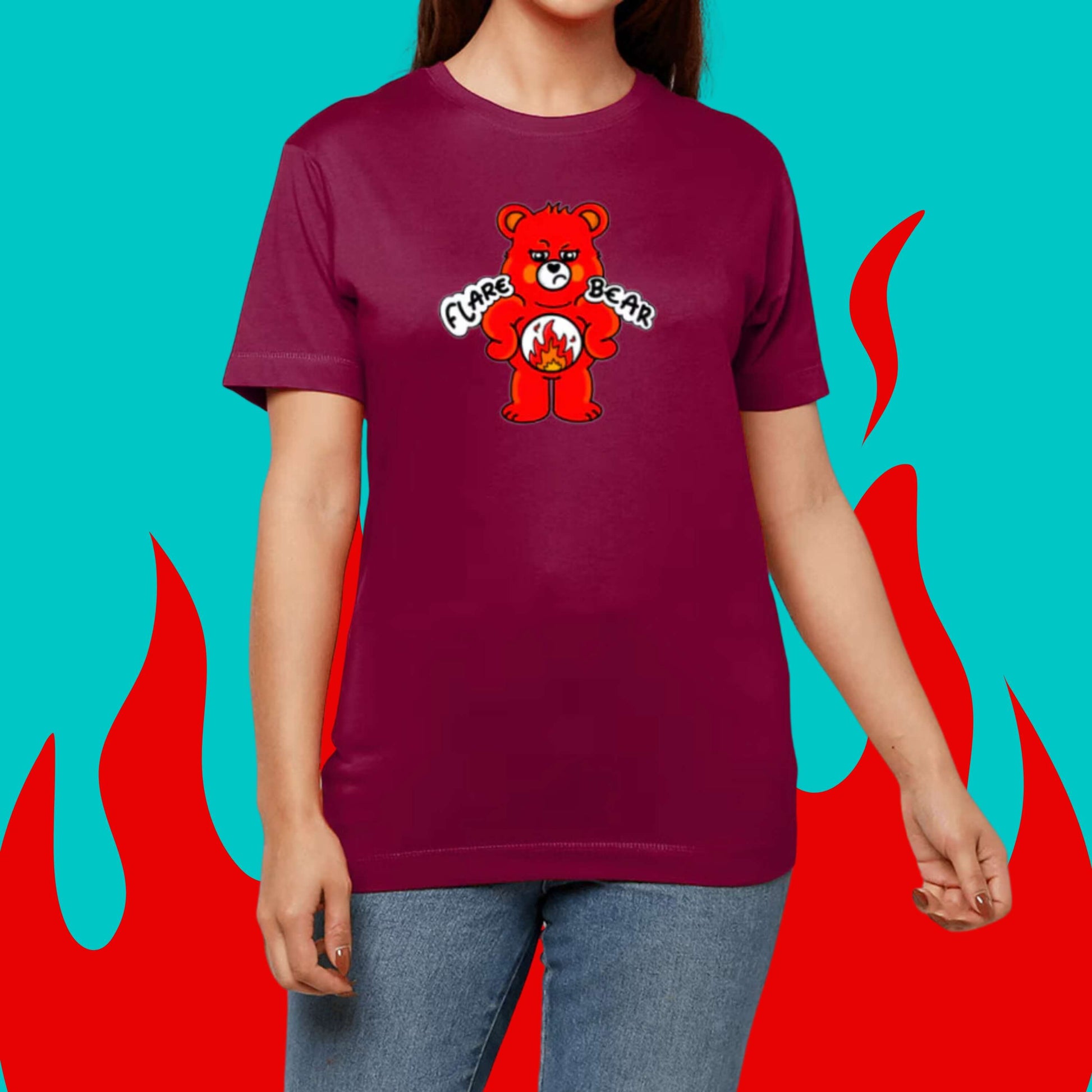 Flare Bear T-shirt being modelled on a blue and red flame background. The cardinal red short sleeve tshirt is of a red bear with a fed up expression and hands on its hips. There is a white circle on its belly with flames inside. Flare Bear is written on the middle. The tshirt is designed to raise awareness for chronic illness flare ups.
