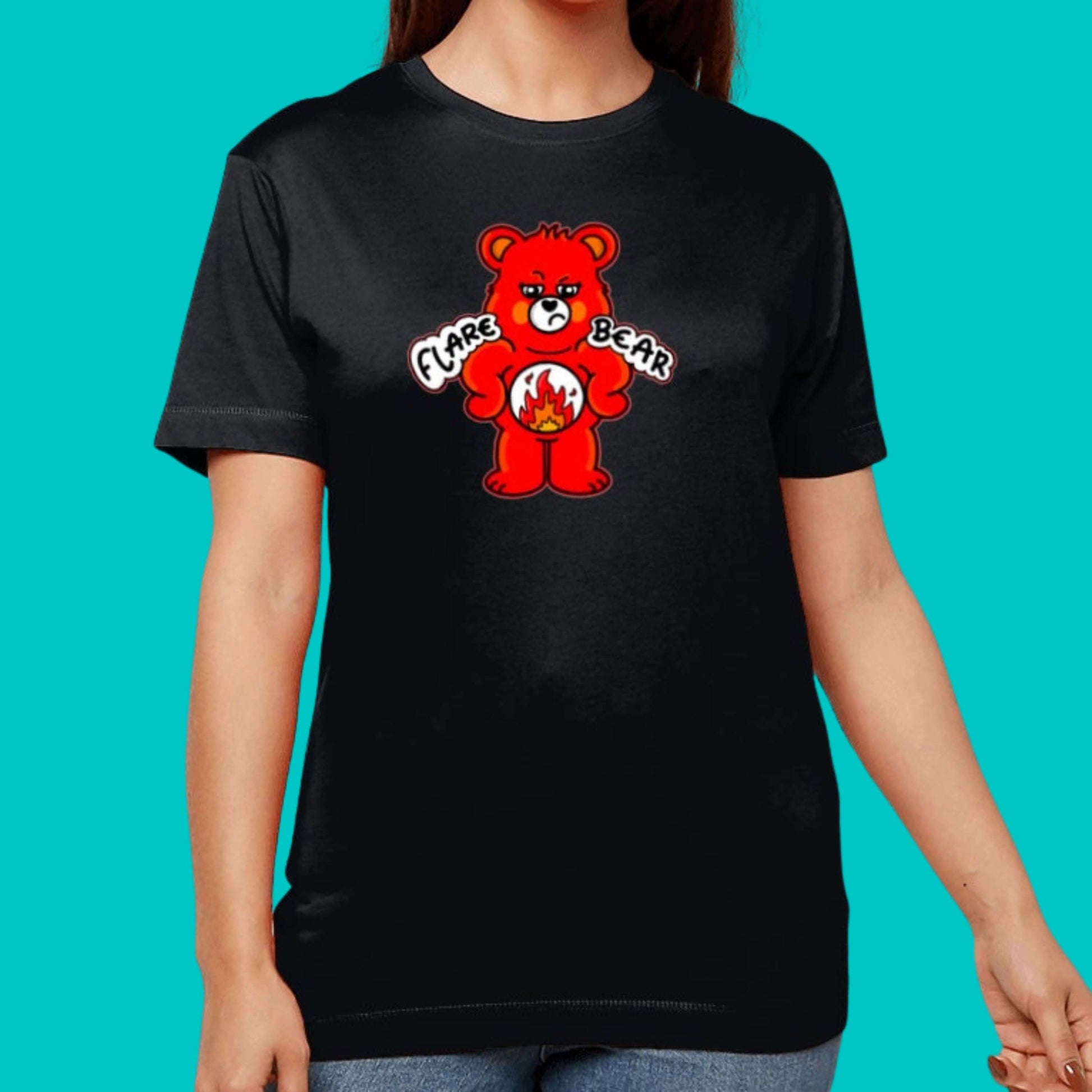 Flare Bear T-shirt being modelled by a femme person on a blue background. The black short sleeve tshirt is of a red bear with a fed up expression and hands on its hips. There is a white circle on its belly with flames inside. Flare Bear is written on the middle. The tshirt is designed to raise awareness for chronic illness flare ups.