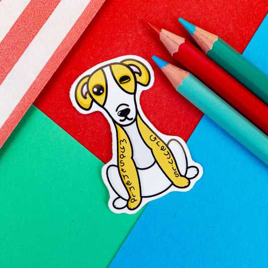 The Myasthenia Greyvis Greyhound Sticker - Myasthenia Gravis on a blue and red background. The sticker is in the shape of a greyhound that is sat down. The greyhound is brown and white with floppy ears and one side of its face is drooping. 'myasthenia greyvis' is written vertically down the dog's legs in black letters. The hand drawn design is raising awareness for Myasthenia Gravis.