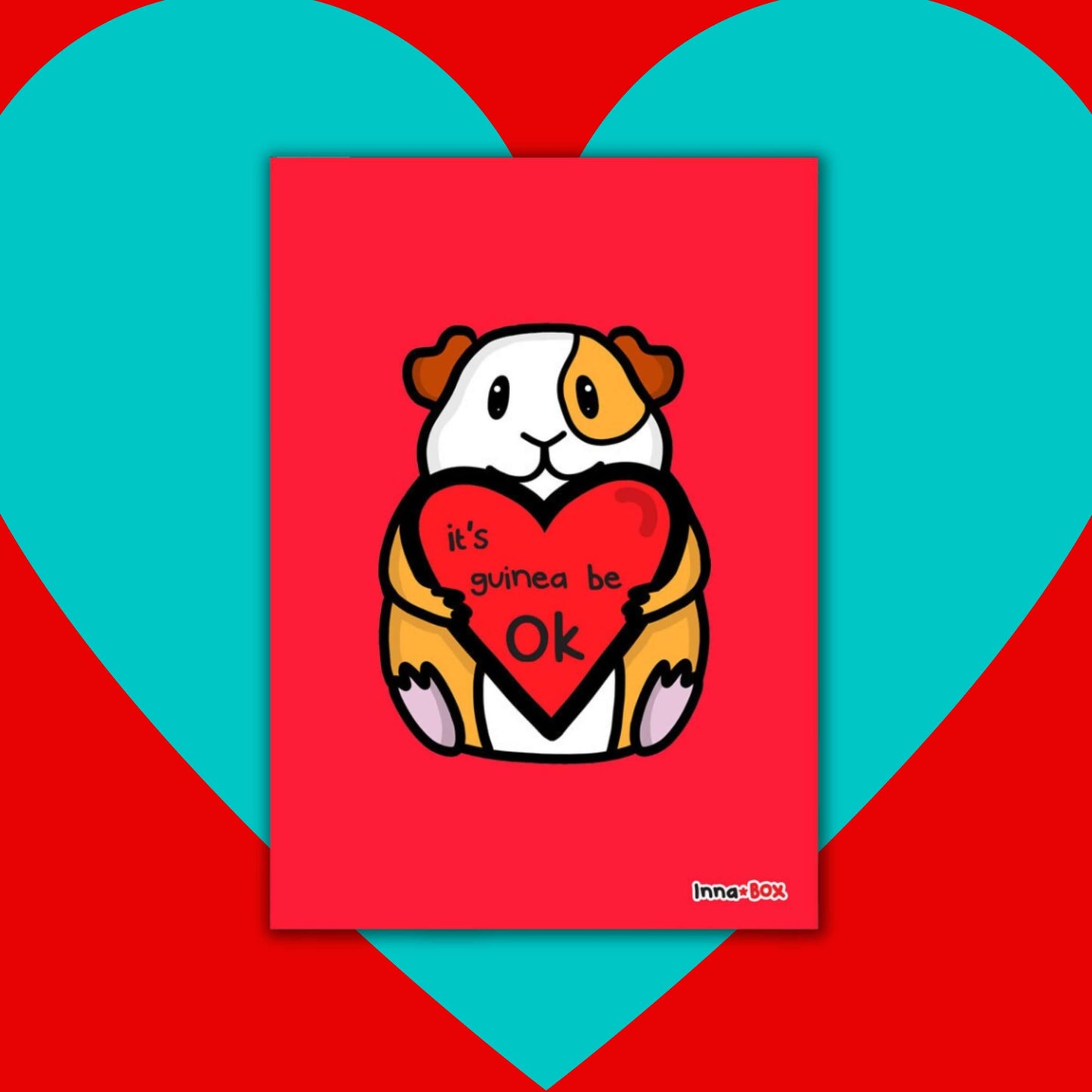 The It's Gonna Be OK Guinea Pig Postcard on a red and blue background. The red postcard print features a cute orange and white smiling guinea pig sat holding a red heart with black text reading 'it's guinea be ok'. The hand drawn design is a reminder for staying positive.