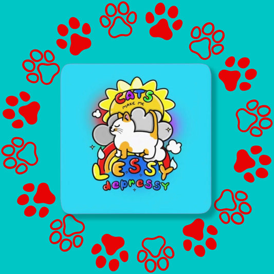 The Cats Make Me Lessy Depressy Coaster on a red and blue paw print background. The blue wooden rounded edges coaster has a smiling orange and white cat with a sunshine, raincloud and rainbow, in rainbow text across this reads 'cats make me lessy depressy'. Hand drawn design to raise awareness for mental health and depression.