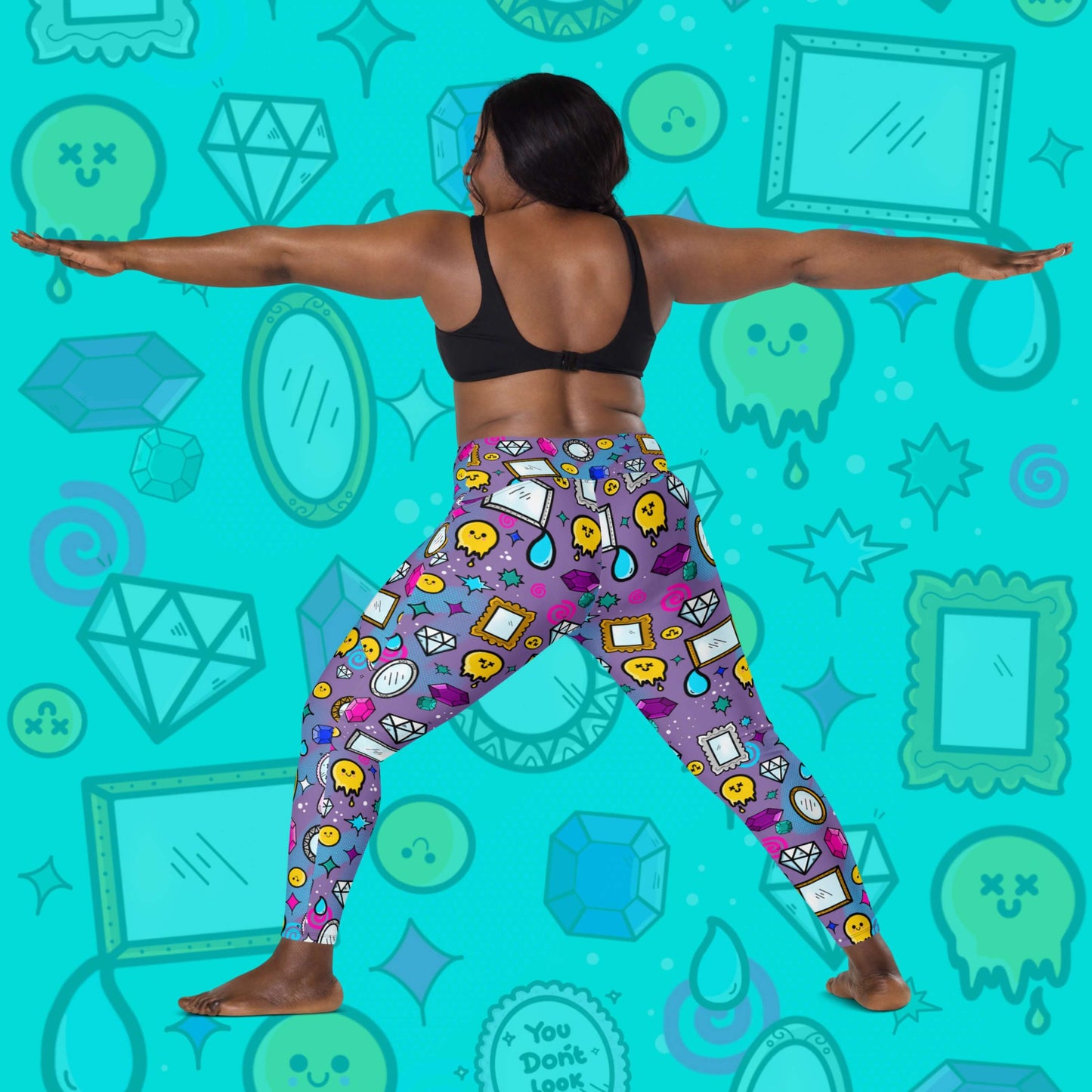 The You Don't Look Sick Leggings with pockets modelled on a blue background with a faded version of the print, the model is doing the warrior yoga pose looking away from camera wearing a black crop and the leggings. The purple base leggings features melting yellow smiley faces, mirrors, gemstones, teardrops, sparkles, swirls and dots with a centre hand held mirror reading 'you don't look sick'. The hand drawn design is raising awareness for invisible illnesses.