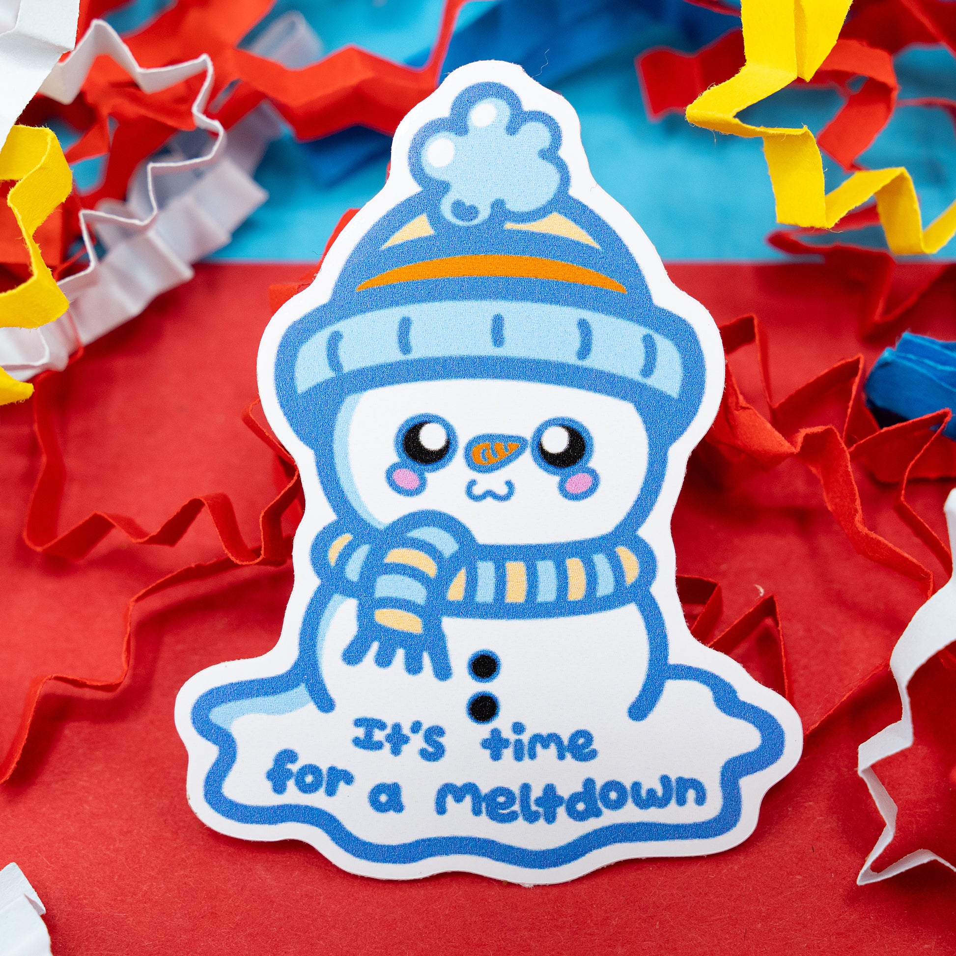 “It’s Time for a Meltdown” vinyl sticker by Innabox featuring a cute snowman in a blue hat and scarf, melting with a cheerful smile. Surrounded by colourful confetti on a red background. Glossy, waterproof sticker designed to raise awareness for sensory overload, stress, and self-care moments.