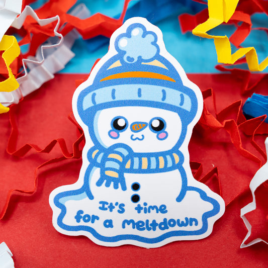 “It’s Time for a Meltdown” vinyl sticker by Innabox featuring a cute snowman in a blue hat and scarf, melting with a cheerful smile. Surrounded by colourful confetti on a red background. Glossy, waterproof sticker designed to raise awareness for sensory overload, stress, and self-care moments.