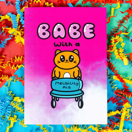 A hot pink and white gradient greeting card with a cute ginger cat holding a blue mobility aid. 'Babe with a mewbility aid' is written on the card. The background of the photo is colourful card confetti. Design inspired by disabilities and chronic illness.