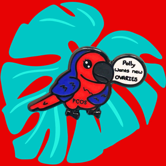 The Pollycystic Ovary Syndrome Parrot Enamel Pin - Polycystic Ovary Syndrome PCOS on a red and blue background. The blue and red parrot pin badge is smiling with a speech bubble reading 'polly wants new ovaries', across its middle reads 'PCOS'. The hand drawn design is raising awareness for Polycystic Ovary Syndrome PCOS.
