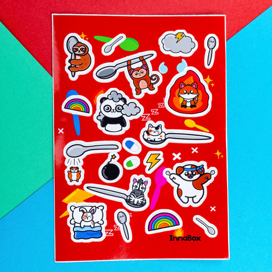 The Spoonie Sticker Sheet - A6 Sticker Sheet on a red, blue and green background. The red a6 vinyl sticker sheet features cute animal illustrations with hidden illnesses represented with spoons, flames, storm clouds, rainbows and pills. The hand illustrated designs are for raising awareness for invisible illnesses. 