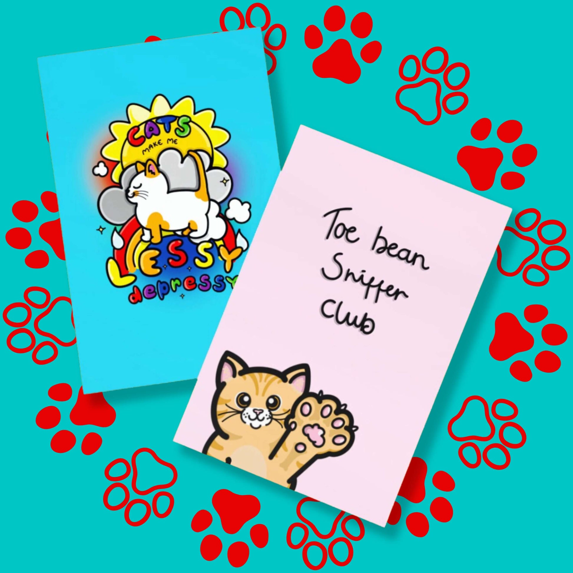 The Toe Bean Sniffer Club Card on a red and blue paw print background with the cats make me lessy depressy blue a6 card underneath. The pastel pink a6 greeting card features a smiling orange cat reaching its paw up with black text above reading 'toe bean sniffer club'.