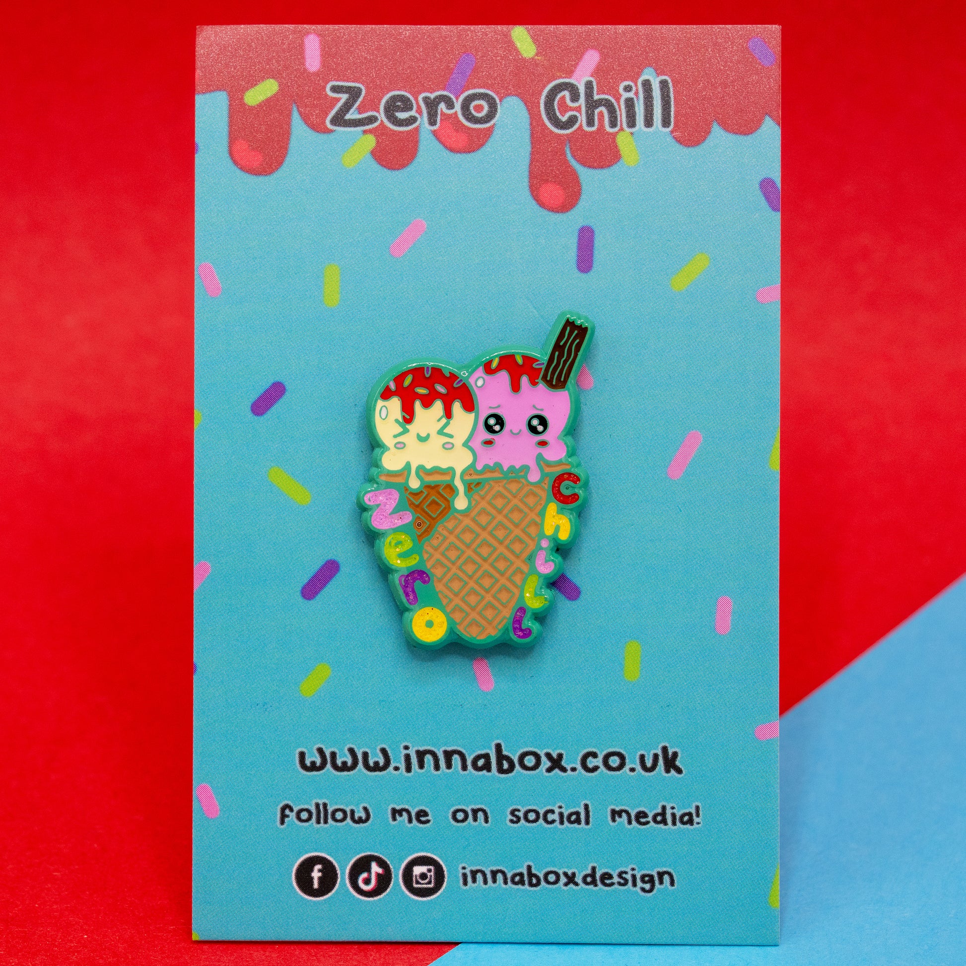Zero Chill Ice-cream Cone Enamel Pin by Innabox, displayed on a colourful blue sprinkle-themed backing card with red drippy details. The pin features two scoops of ice cream with kawaii-style faces and a flake, in a waffle cone with the words “Zero Chill” in rainbow letters. A cute, awareness-raising pin designed to uplift those with hidden disabilities.