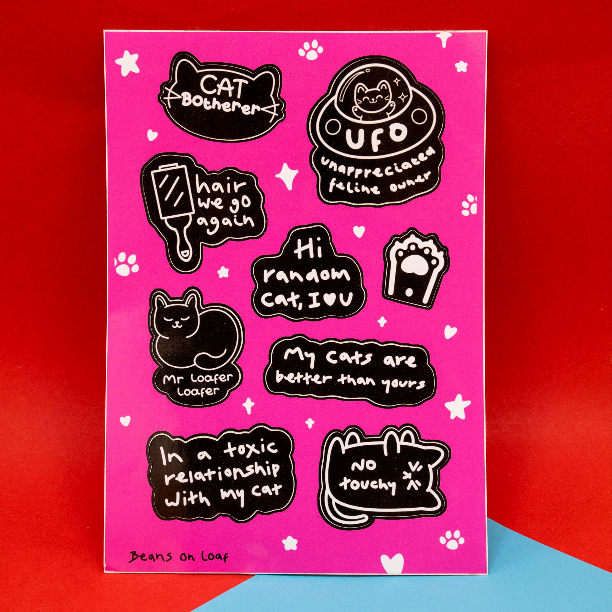 A6 Cat Parent sticker sheet by Innabox featuring black and white illustrated cat themed stickers on a bright pink background. Designs include phrases such as Cat Botherer, UFO unappreciated feline owner, Hi random cat I luv u, My cats are better than yours, In a toxic relationship with my cat and No touchy, plus cute cat illustrations, paw prints, hearts and stars. Fun cat lover sticker sheet.